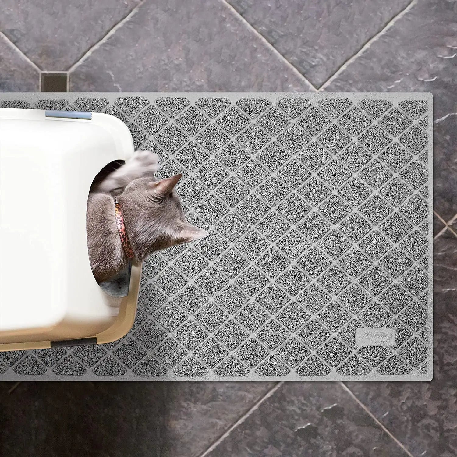 Gray textured mat with a cat peeking out from a hole, on a tiled floor.