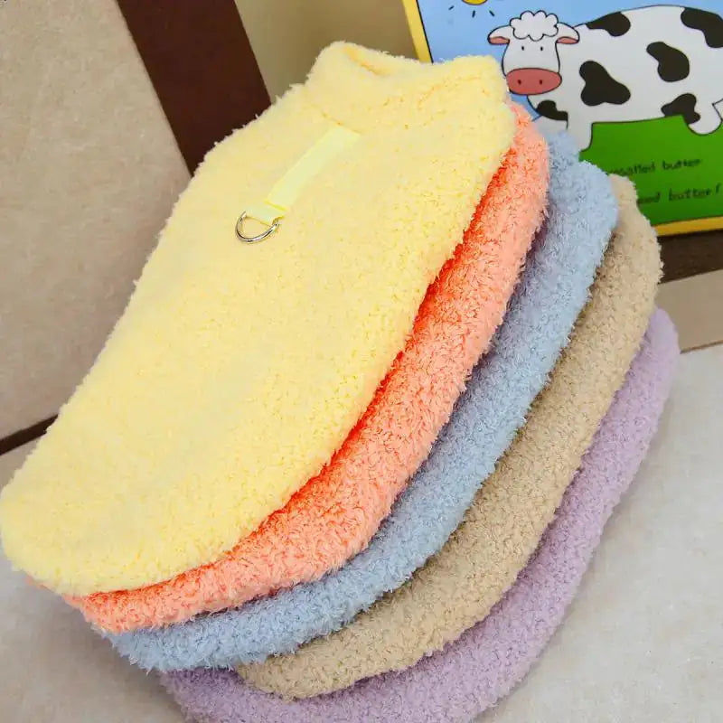 Stack of colorful fluffy towels on a surface with a cartoon cow in the background.