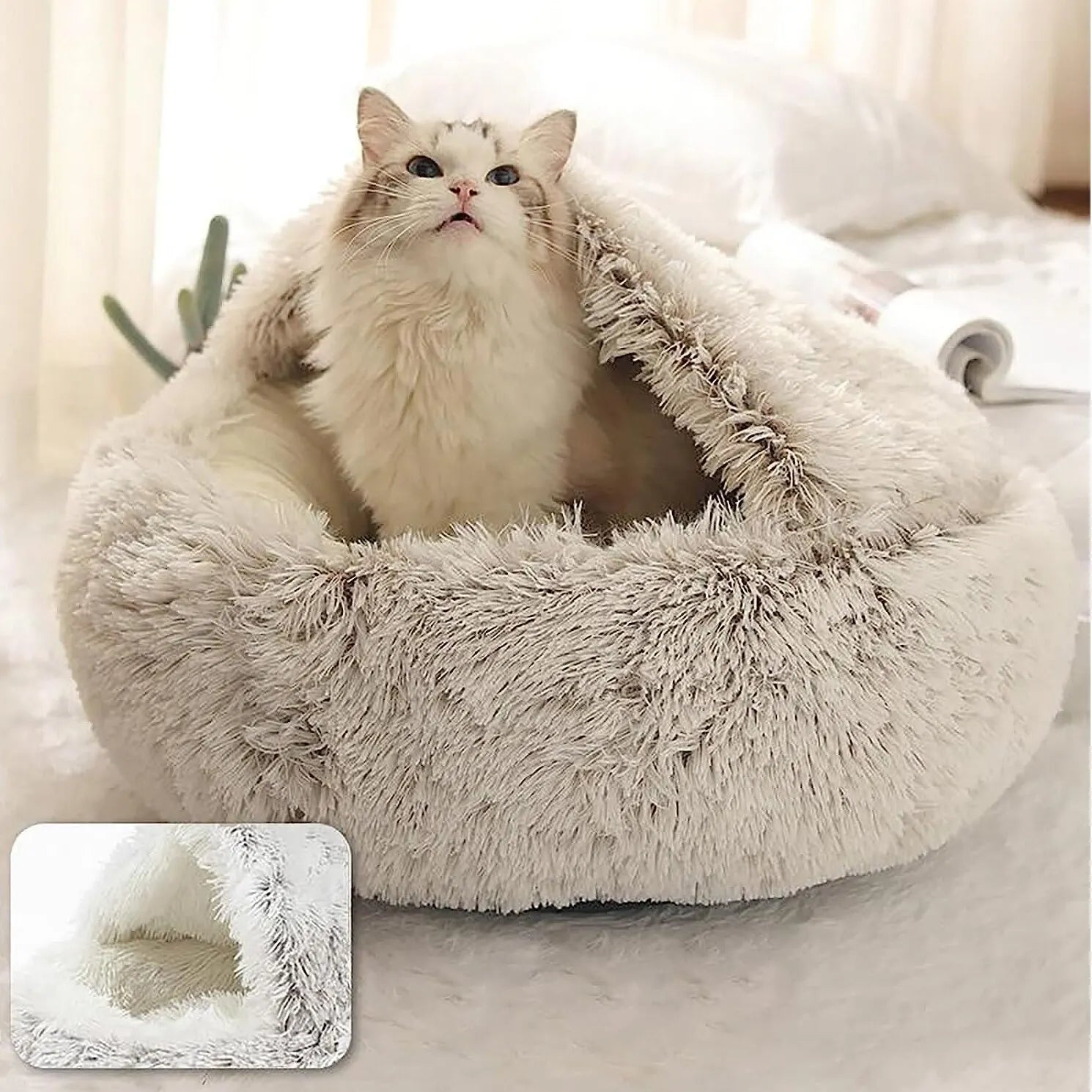 Fluffy white cat bed with a fluffy white cat inside, on a soft surface.