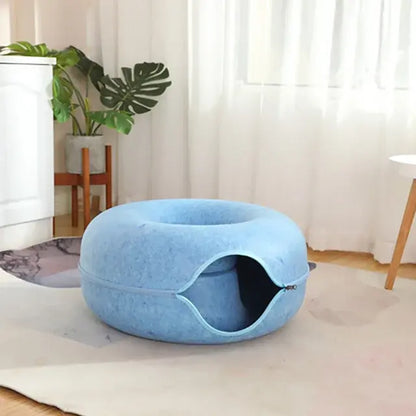 Blue pet bed in a room with white curtains and a plant.